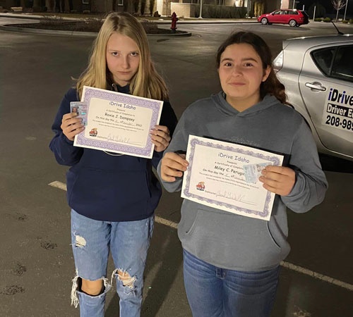 2 students holding their certificates and new driver licenses